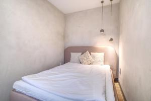 a bedroom with a bed with white sheets and pillows at Apartament Gris in Sopot
