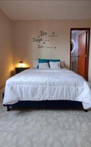 um quarto com uma grande cama branca com escrita na parede em Lovely 3 bedroom rental unit. 4th floor. em Barranquilla