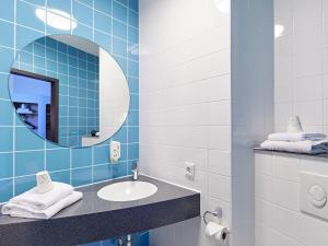 a blue tiled bathroom with a sink and a mirror at B&B HOTEL Münster Hafen in Münster