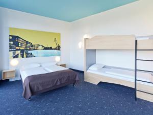 B&B HOTEL Münster Hafen في مونستر: غرفة نوم مع سرير وسرير بطابقين