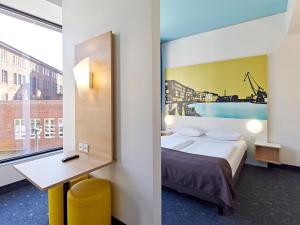 ein Hotelzimmer mit einem Bett, einem Schreibtisch und einem Fenster in der Unterkunft B&B HOTEL Münster Hafen in Münster