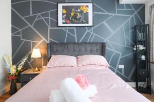 ein Schlafzimmer mit einem rosa Bett mit einem ausgestopften Tier darauf in der Unterkunft Jazzy 2BR Enfield Crib - Parking, Wi-Fi & Private Garden in Ponders End