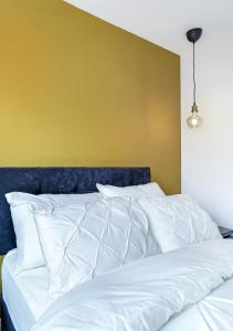 a bed with white pillows and a yellow wall at The Burrow in Sion Mills