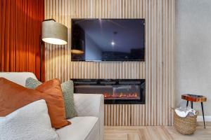 a living room with a fireplace with a tv above it at The Burrow in Sion Mills