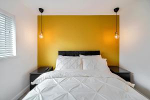 a bedroom with a white bed with a yellow wall at The Burrow in Sion Mills