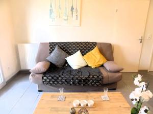 a living room with a couch with pillows on it at Royan - CONFORTABLE APPARTEMENT - TERRASSE et JARDINET PRIVATIF - WIFI in Royan