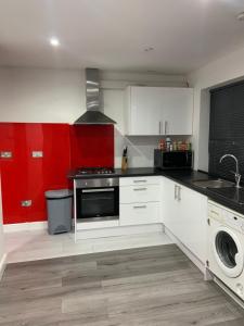 a kitchen with white cabinets and red walls at Inviting 2-Bed fully Furnished House-High Wycombe in High Wycombe