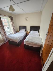 2 Betten in einem Zimmer mit rotem Teppich in der Unterkunft The New Inn in Thornton Dale