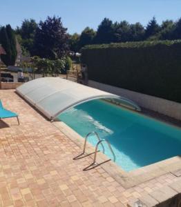 una piscina con cubierta en un patio de ladrillo en Domaine de karoli, en Barneville-sur-Seine