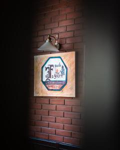 a sign on a brick wall with a light at Al Fogolâr Rooms & Osteria with Saunaland in Tolmezzo