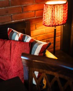 uma mesa com um candeeiro ao lado de uma cama com almofadas em Al Fogolâr Rooms & Osteria with Saunaland em Tolmezzo