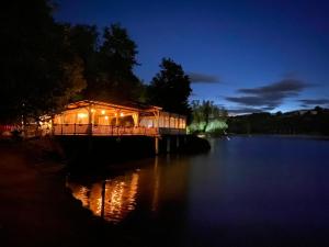 a lit up house on a pier over a lake at night at Montaigu Plage in Montaigu-de-Quercy