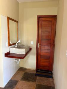 a bathroom with a sink and a wooden door at Imperio dos Bambus Suites in Jijoca de Jericoacoara