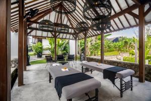 a patio with two tables and chairs and chandeliers at Bloom Resort Bali by BaliSuperHost in Canggu