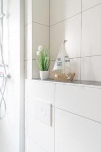 a white bathroom with a shelf with a boat on it at Ferienwohnug Harzglück in Clausthal-Zellerfeld