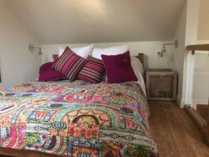 ein Schlafzimmer mit einem Bett mit einer bunten Decke und Kissen in der Unterkunft The Bike Shed, Near Brill in Aylesbury