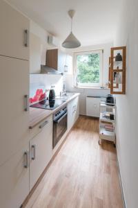 a kitchen with white cabinets and a wooden floor at Ferienwohnug Harzglück in Clausthal-Zellerfeld +4 photos