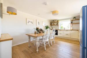 uma cozinha com uma mesa de madeira e cadeiras brancas em Chic Family Barn, edge of Frome + country views em Frome