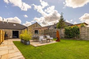 um pátio com cadeiras e um guarda-sol num quintal em Chic Family Barn, edge of Frome + country views em Frome