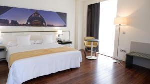 ein Hotelzimmer mit einem großen Bett und einem Schreibtisch in der Unterkunft Primus Valencia in Valencia