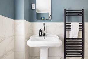 een badkamer met een witte wastafel en een spiegel bij Chic Family Barn, edge of Frome + country views in Frome