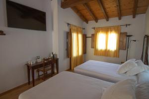 a bedroom with two beds and a desk and a television at Hotel Rural Abadía de Yuste in Cuacos de Yuste