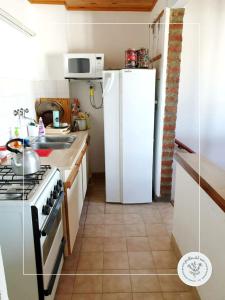 a kitchen with a stove and a white refrigerator at Jarillas del Mar in Las Grutas