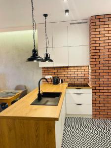 a kitchen with a sink and a brick wall at Drewnowska 77 Prime Apartment in Łódź
