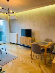 a living room with a table and a flat screen tv at Drewnowska 77 Prime Apartment in Łódź