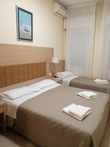twee bedden in een hotelkamer met handdoeken erop bij Hotel Cuba Aeroport Restaurant in Rimini