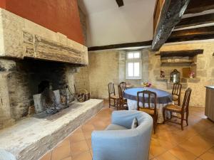 a living room with a table and a fireplace at Le Gîte du Prieuré in Bellefond +45 photos