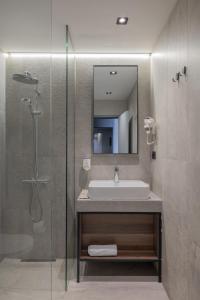 a bathroom with a sink and a shower with a mirror at Hotel Square by MARGO in Pristina