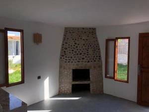 a room with a stone fireplace with two windows at Surf HouseMaroc in Essaouira