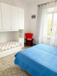 a bedroom with a bed and a red chair at Villino Mirella a Marina di Cecina in Marina di Cecina