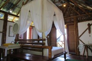 um quarto com uma cama com cortinas brancas em Pousada Sabambugi em Baía Formosa