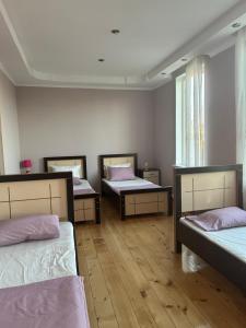 three beds in a room with wooden floors at Guesthouse TEA in Kutaisi