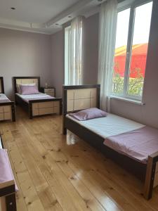 two beds in a room with two windows at Guesthouse TEA in Kutaisi
