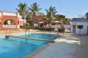 een groot zwembad op een binnenplaats met palmbomen bij Hotel Takana in Ngaparou