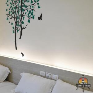 a bedroom with a tree and birds on the wall at Guang's Tribe Homestay in Magong