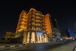 a building is lit up at night next to a street at فنـــــــــدق ايليفــــــــــــار Elevar Hotel in Al Khobar