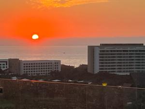 a sunset over a city with buildings and the ocean at Grand Luxxe with free Golf in Nuevo Vallarta 