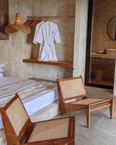 a bedroom with a bed and two chairs and a mirror at Swell Shacks in Matara