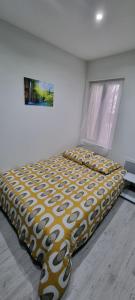 Bett in einem Schlafzimmer mit gelber und weißer Decke in der Unterkunft Studio Aloe tout confort rénové in Saint-Quentin