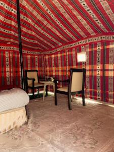 a bedroom with a bed and two chairs and a table at Hamood desert local camp in Al Wāşil