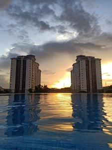 uma piscina em frente a dois edifícios de apartamentos ao pôr do sol em Suria Kipark Damansara 3R2B 950sq ft Apartment em Kuala Lumpur