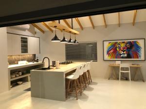 a kitchen with a large island with chairs in it at Modern Bush Living in Marloth Park
