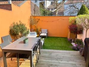een patio met een tafel en stoelen en een tuin bij Maison LILLE 6 personnes avec Jardin in Lille