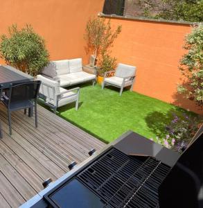 een achtertuin met een grill, een bank en gras bij Maison LILLE 6 personnes avec Jardin in Lille