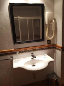 a bathroom with a sink and a mirror and a phone at Hotel Condes De Lemos España in Monforte de Lemos