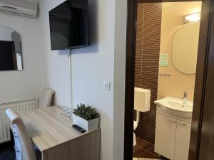 Habitación con mesa, lavabo y TV. en Pansion Komfor Fitea, en Osijek